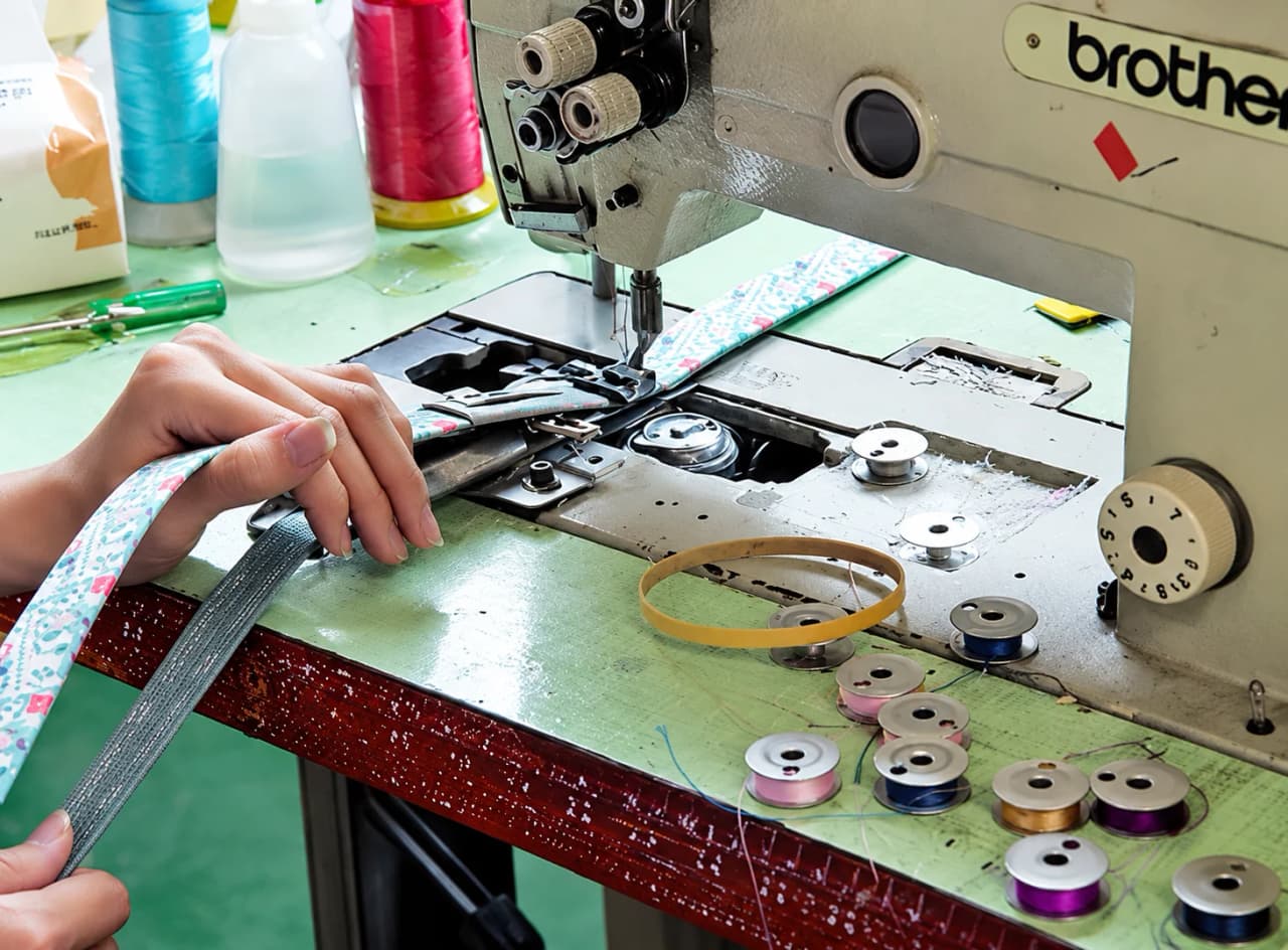 Worker guiding material through an industrial sewing machine