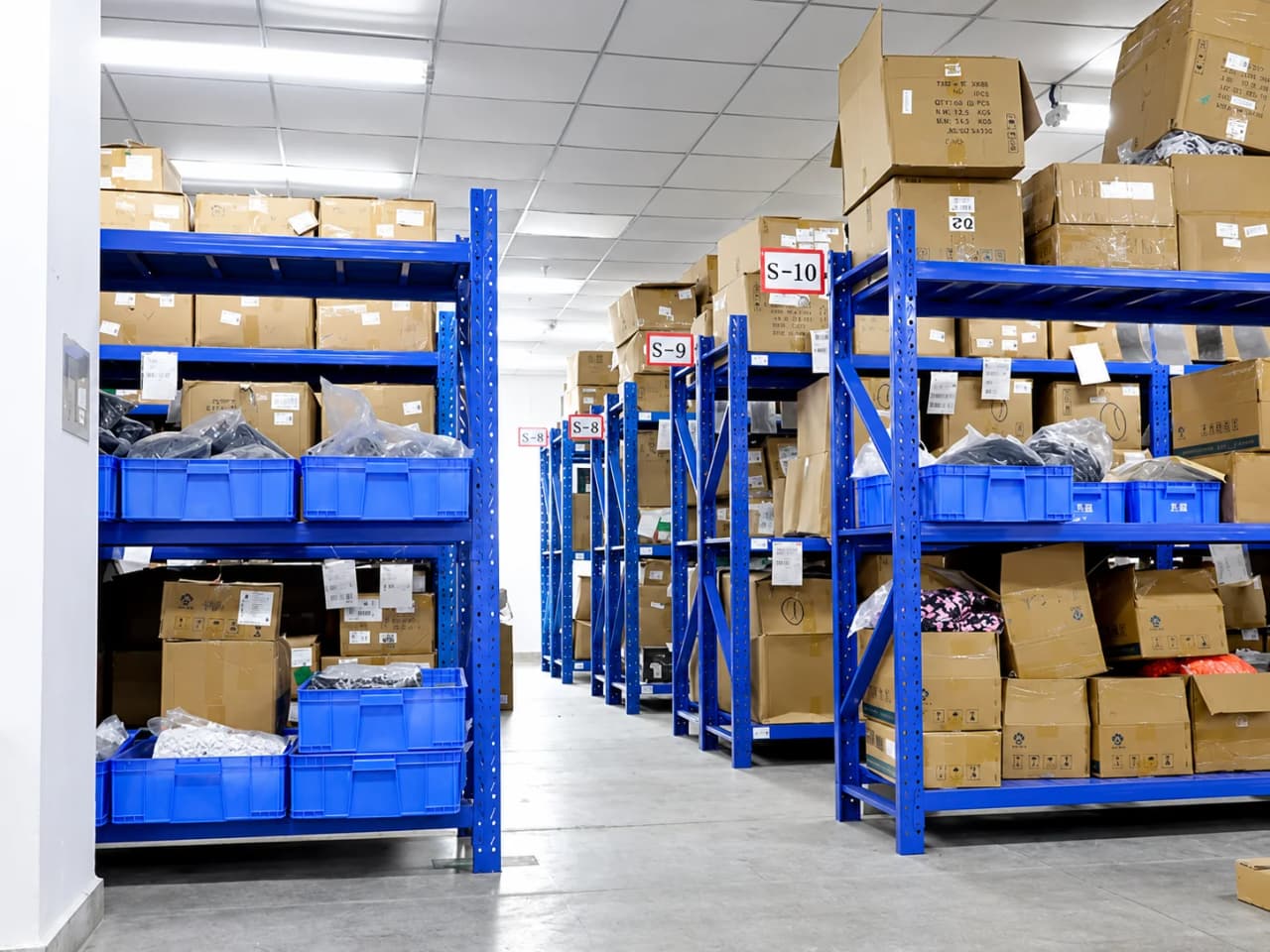 Warehouse aisle with blue shelving, cartons and storage bins